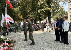 grupa osób podczas uroczystości przed Pomnikiem Ofiar Komunizmu w  Łodzi